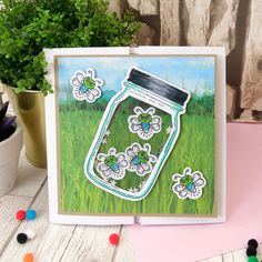 a card with flowers in a mason jar on the front and green grass behind it