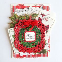 a close up of a christmas card with a wreath and holly on the front, surrounded by other cards