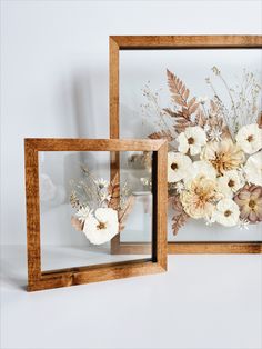 two wooden frames with flowers in them on a white surface and one is holding a glass vase