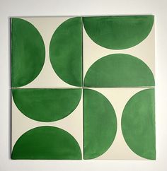 four green and white circles on a square tile wall hanging in front of a white wall