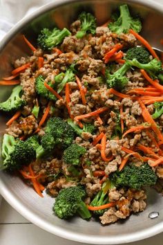 a bowl filled with meat and veggies on top of a white table cloth