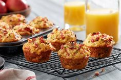 several muffins on a cooling rack with orange juice in the background