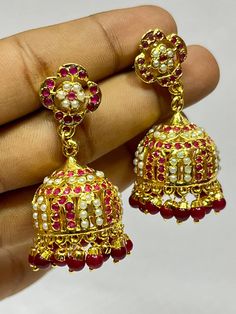 "Experience the royal heritage of Hyderabadi jewelry with this exquisite Jhumka set, handcrafted with love and precision. This stunning piece features: - Intricately designed brass Jhumkas adorned with Polki stones and Quartz stones - Delicate filigree work and textured details, reminiscent of traditional Hyderabadi craftsmanship - Dangling tassels that add movement and flair - Comfortable ear wires and a secure clasp for all-day wear Inspired by the rich cultural legacy of Hyderabad, this Jhumk Red Bollywood Jhumkas With Intricate Design, Red Kundan Jhumkas With Intricate Design, Gift Brass Jhumkas With Latkans, Red Jhumkas With Intricate Design For Diwali, Festive Red Jhumkas With Intricate Design, Traditional Brass Jhumkas For Navratri, Bollywood Ruby Jhumkas For Festivals, Ruby Bollywood Jhumkas For Festivals, Brass Jhumkas For Festival Gifts