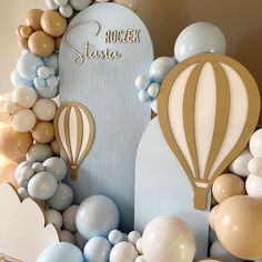 a balloon arch is surrounded by balloons and streamers in blue, gold and white