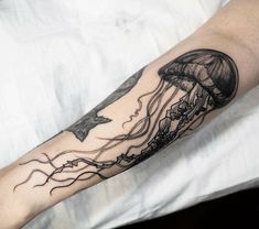 a black and white photo of a jellyfish tattoo on the arm