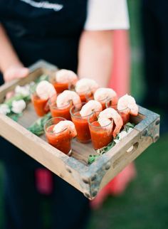 small appetizers are arranged on a wooden tray with garnish and herbs