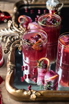 three glasses filled with cranberry punch and garnished with orange slices on a tray