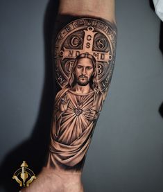 a man's arm with a tattoo of jesus on it and the cross in the center