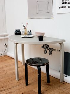 a small table with a stool underneath it in a room that has wood floors and white walls