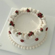 a cake with white frosting and red roses on it