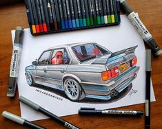 a drawing of a car on paper next to markers and crayons