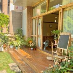 a wooden deck with chairs and potted plants on it in front of a house