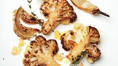 roasted cauliflower with herbs and garlic on a white plate next to an orange slice