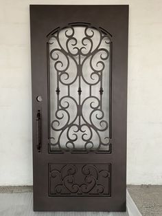 an ornate iron door on the side of a building with white walls and concrete flooring