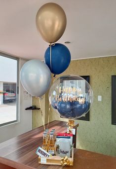 some balloons and bottles on a table in front of a window with the words happy birthday written on it