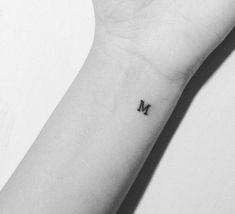 a small wrist tattoo with the letter m on it