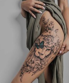 a woman's thigh with a lion and flowers tattoo on it