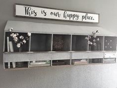 this is our happy place sign and bookshelf with flowers on the shelf above it