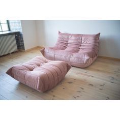 a pink chair and ottoman sitting on top of a wooden floor