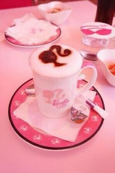 a pink table topped with plates and cups filled with food