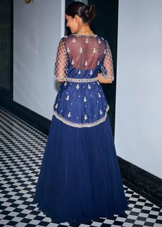 Midnight blue hand embroidered asymmetric peplum. It is embroidered with sequins, stones and beads, features a v neckline and handmade tassels at the sleeves. It is paired with a georgette flowy skirt and a net dupatta. Designer Sequined V-neck Dress, Elegant Blue Choli With Sequins, Designer Blue Sequined Sharara, Traditional Blue Choli For Evening, Evening Blue Lehenga With Mirror Work, Sequin Peplum Set For Reception, Reception Peplum Set With Sequins, Blue Embellished Evening Lehenga, Blue Embellished Lehenga For Evening