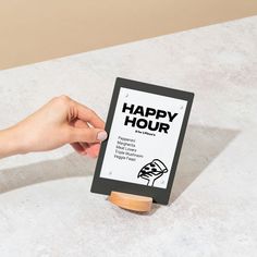 a hand holding a sign that says happy hour on the front and back of it