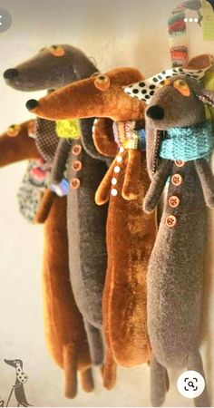 three stuffed dogs hanging from a hook on a wall with buttons and ribbons attached to them