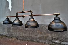 three metal lamps hanging from a wall