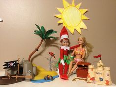 two elf dolls sitting on top of a table next to toys and palm trees in the background