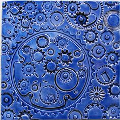 a blue tile with gears and flowers in the shape of a circle on top of it