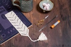 some craft supplies are sitting on a table next to a book, scissors and thread