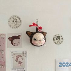 there is a small stuffed animal hanging on the wall next to other magnets and badges