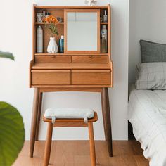 a wooden desk with a mirror, stool and bed in the corner next to it