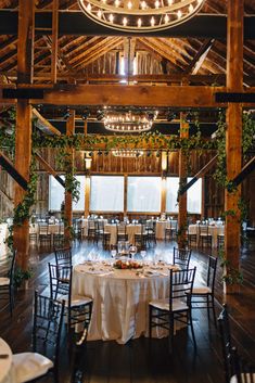 the inside of a barn with tables and chairs set up for a formal dinner or function