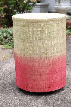 a large round basket sitting on top of a cement ground next to a planter