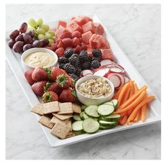 a platter filled with fruit, vegetables and crackers