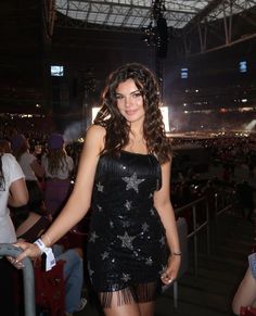 a woman in a short black dress posing for the camera at a concert or show