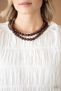 a woman wearing a necklace with brown beads