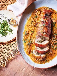 a white plate topped with meat covered in gravy and garnished with parsley