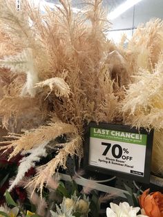 the sale sign is displayed in front of dried flowers