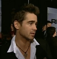 a man in a black suit and white shirt talking to someone on the red carpet