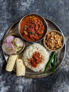 a metal plate topped with rice, meat and veggies next to other foods