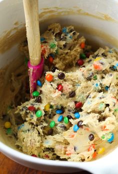 a mixing bowl filled with batter and sprinkles on top of a wooden table