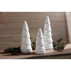 three white christmas trees sitting on top of a wooden table