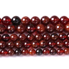 red tiger eye beads are lined up on a white surface