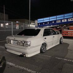 a white car parked in a parking lot next to a blue dump truck at night