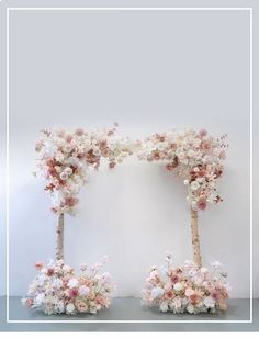 two wooden sticks with flowers on them in front of a white wall