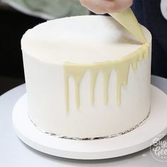 someone is decorating a white cake with yellow icing