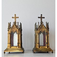 two small gold crosses sitting next to each other on top of a white countertop