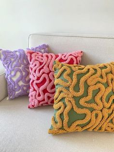 three decorative pillows on a white couch